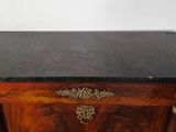 an old wooden table with a marble top on a black floor