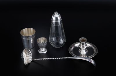 an assortment of silver and glass items on a black surface