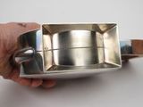 a person holding a silver plate with a wooden handle