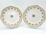 pair of plates with gold and green designs on them on a white surface