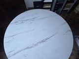 a round table with a white marble top in the middle of a room