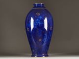 a blue vase sitting on a white table with a gray background