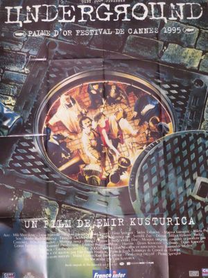 une vieille affiche de cinéma pour « Underground », avec en arrière-plan la photo d'un groupe de personnes