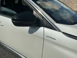 une voiture blanche garée sur un parking, près d'un mur de briques