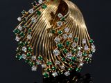 a close up of a gold broochle with green and white stones