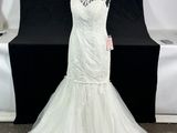 a white wedding dress on a mannequin stand in front of a black backdrop