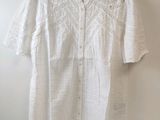 une chemise blanche accrochée au mur à côté d'un cintre en bois