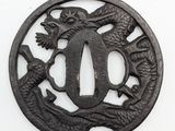 an old iron tsuba with a dragon and a fish on it