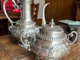 three silver teapots sitting on a wooden table