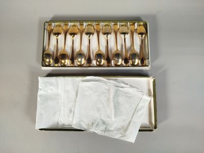 une boîte contenant des cuillères en or et des serviettes, posée sur une table