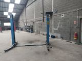 une photo d'un garage avec un pont élévateur bleu au milieu
