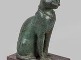 statue of a cat sitting on a base on a white background
