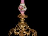 a gold and pink vase on a stand with a black background