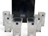six crystal shot glasses in front of a black box on a white surface