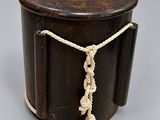 an old wooden box with a rope around it on a gray surface