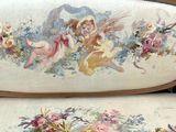 une photo d'un canapé orné d'un motif représentant des anges et des fleurs