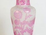 a pink vase sitting on a table with a white wall in the background