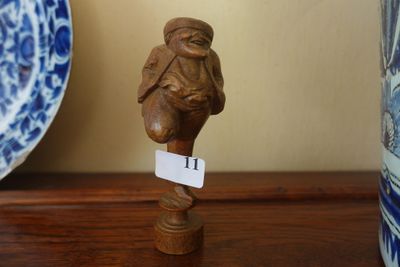 une petite figurine posée sur une table, à côté d'une assiette bleue et blanche