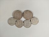 six silver coins sitting on top of each other on a white surface
