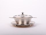 an antique silver plate with a lid and saucer on a white background