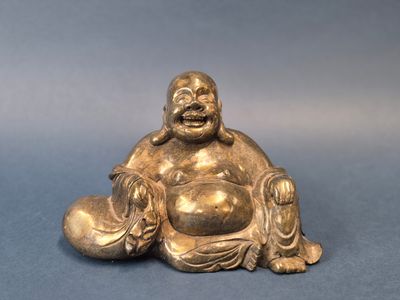 statue d'un Bouddha souriant, assis par terre, tenant un bol entre ses mains