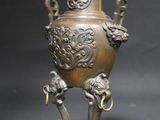 an old bronze vase with two birds on it sitting on a stand