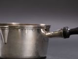 a silver pot with a wooden handle on a table