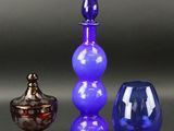 trois vases en verre de couleurs différentes posés les uns à côté des autres sur une table