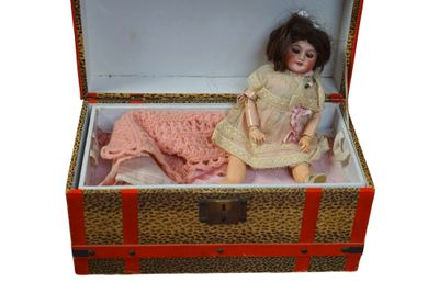a doll sitting in a suitcase with a blanket on it