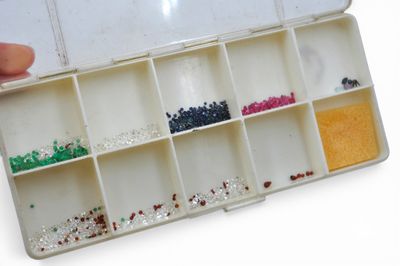 a person holding a box with different colored beads in it