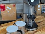 une cafetière posée sur une table en bois à côté d'un mixeur