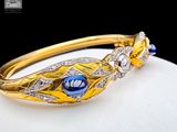 an image of a close up of a gold bracelet with a blue stone