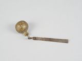 a gold spoon with a ball on it on a white surface