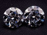 a pair of round cut diamonds on a black surface