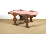 une table en bois posée à même le sol, dont le plateau est recouvert de carreaux roses