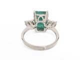 a close up of a ring with a green stone and diamonds