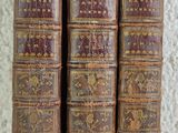 three old books are stacked on top of each other on a table