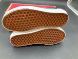 vans off the wall slip - ons in red and white are on a black surface