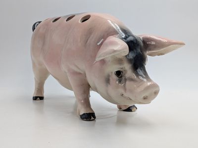 a ceramic pig figurine that is standing on a white surface