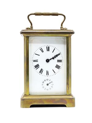 une petite horloge en laiton avec des chiffres romains sur le cadran