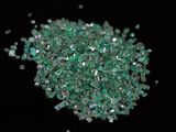 some green crystals are scattered on a black surface