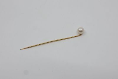 une broche composée d'une perle et d'or sur fond blanc
