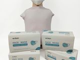 trois boîtes de masques sont posées à côté d'une tête de mannequin