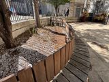 a wooden bench sitting next to a fence on the side of the street