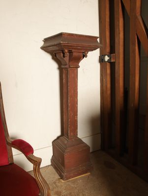 une chaise rouge dans un coin de la pièce, à côté d'une grande colonne en bois