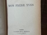 un livre posé sur une table, avec une pile de livres en arrière-plan