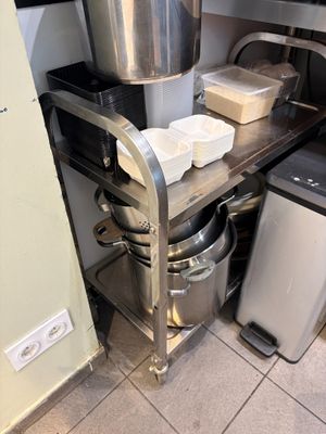 a metal shelf with pots and pans on it in a kitchen