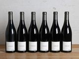six bouteilles de vin sont alignées sur une table en bois