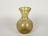 un petit vase jaune posé sur une surface blanche