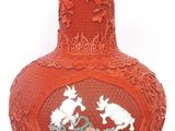 a red vase that has a picture of two birds on it